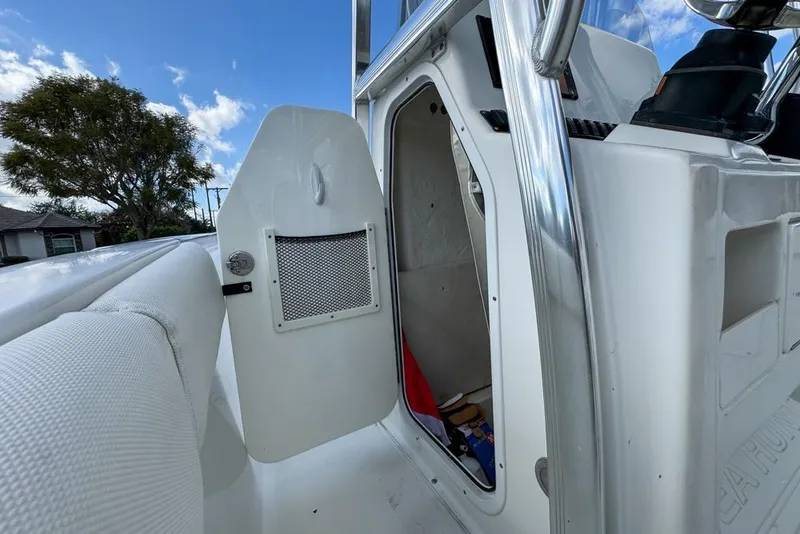 Slide: The Image of 2016 Sea Hunt Ultra 211 boat interior storage compartment with open door, under blue sky. - 104