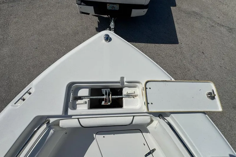 Slide: The Image of 2016 Sea Hunt Ultra 211 boat bow with open storage compartment, parked on pavement. - 61