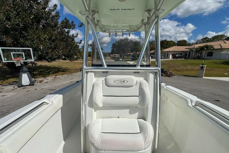 Slide: The Image of 2016 Sea Hunt Ultra 211 boat interior with white seating and T-top, parked in a residential area. - 73