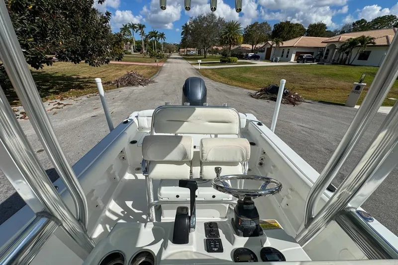 Slide: The Image of 2016 Sea Hunt Ultra 211 boat interior with steering wheel and seating, parked on a residential street. - 79