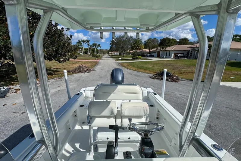 Slide: The Image of 2016 Sea Hunt Ultra 211 boat interior with steering wheel and seating, parked on a residential street. - 81