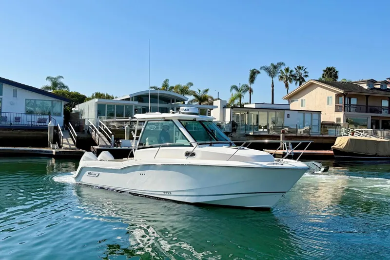 The Image of 2025 Boston Whaler 285 Conquest boat cruising in a scenic waterfront setting. - 0