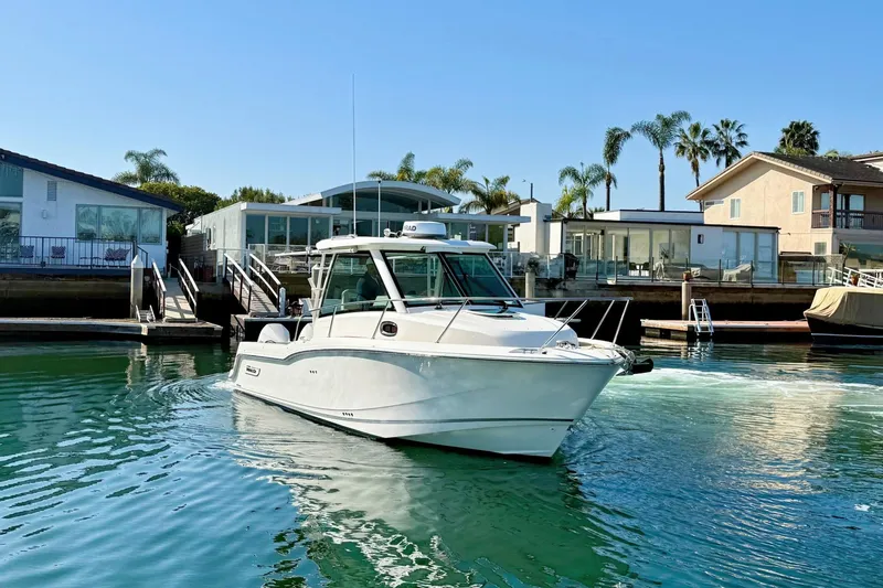 Slide: The Image of 2025 Boston Whaler 285 Conquest boat cruising in a scenic waterfront setting. - 10