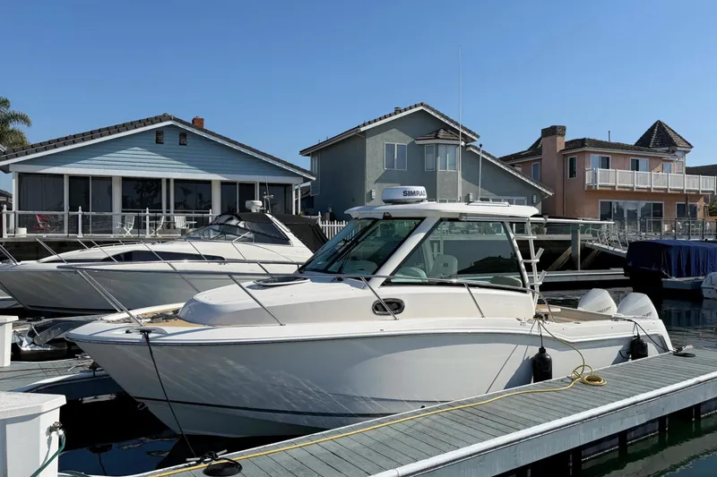 Slide: The Image of 2025 Boston Whaler 285 Conquest docked near waterfront homes. - 12