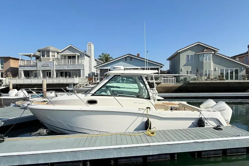 Slide: The Image of 2025 Boston Whaler 285 Conquest docked near waterfront homes under clear blue sky. - 13