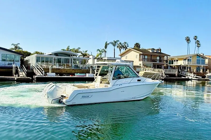 Slide: The Image of 2025 Boston Whaler 285 Conquest boat cruising near waterfront homes. - 3