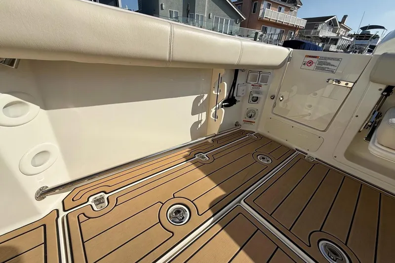 Slide: The Image of 2025 Boston Whaler 285 Conquest boat interior with teak flooring and cushioned seating. - 30