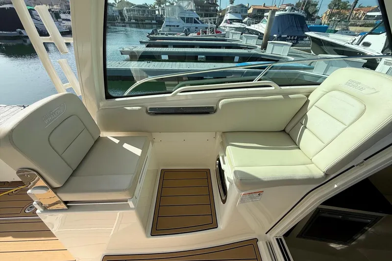 Slide: The Image of 2025 Boston Whaler 285 Conquest interior seating with marina view. - 35