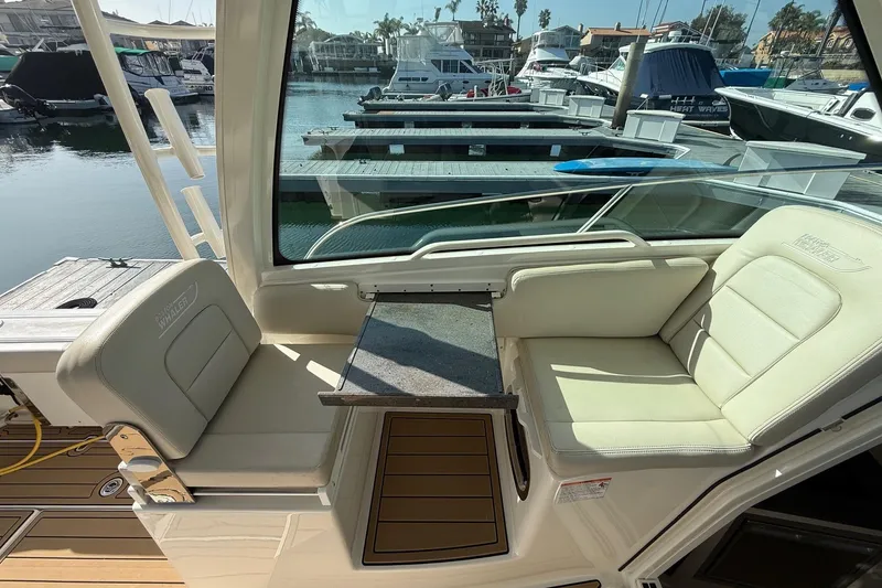 Slide: The Image of 2025 Boston Whaler 285 Conquest interior seating with table, docked at marina. - 36