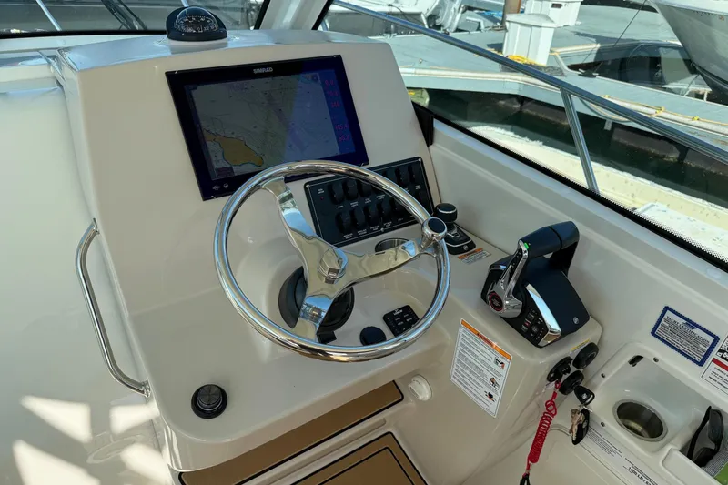 Slide: The Image of 2025 Boston Whaler 285 Conquest helm with steering wheel, navigation display, and controls. - 38