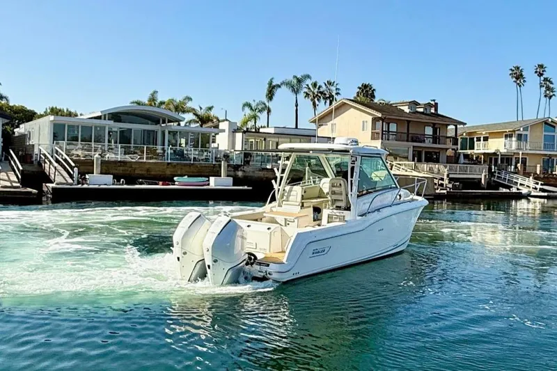 Slide: The Image of 2025 Boston Whaler 285 Conquest boat cruising near waterfront homes. - 4