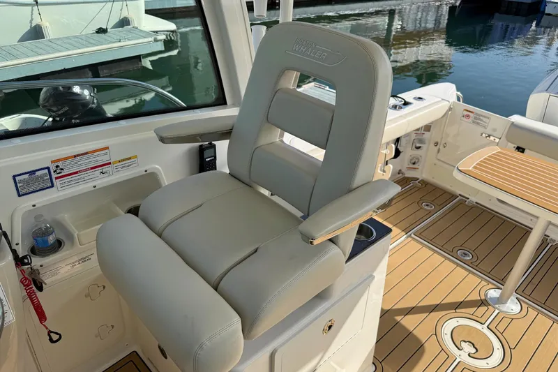 Slide: The Image of 2025 Boston Whaler 285 Conquest boat interior with captain's chair and teak flooring. - 42