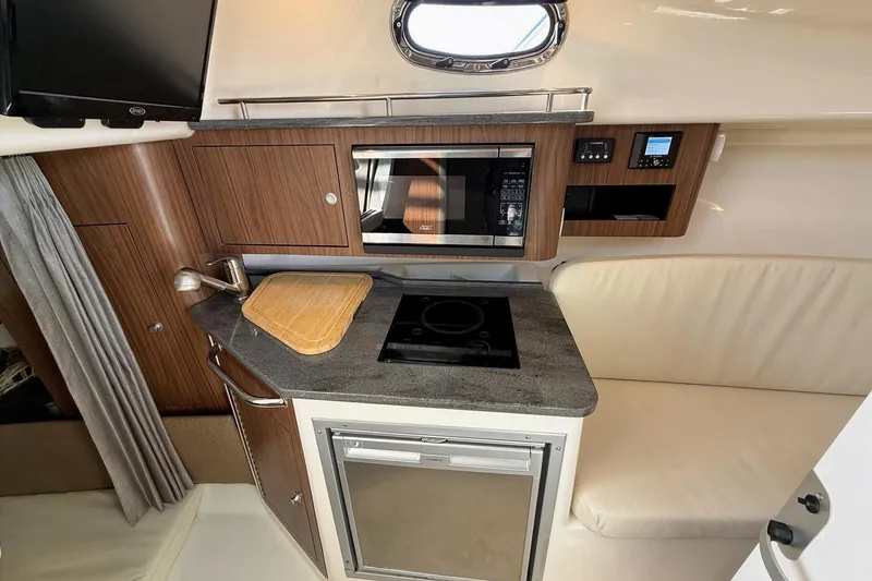 Slide: The Image of 2025 Boston Whaler 285 Conquest interior kitchen with modern appliances and wood cabinetry. - 45
