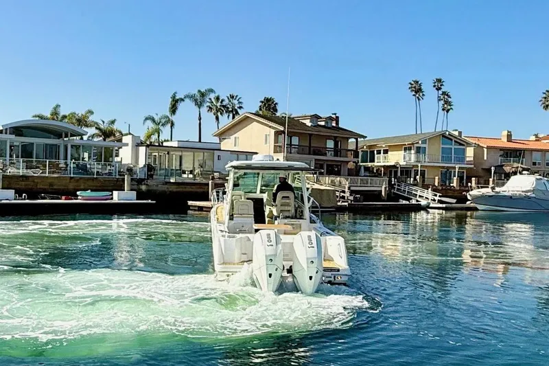 Slide: The Image of 2025 Boston Whaler 285 Conquest boat cruising in a sunny waterfront neighborhood. - 5