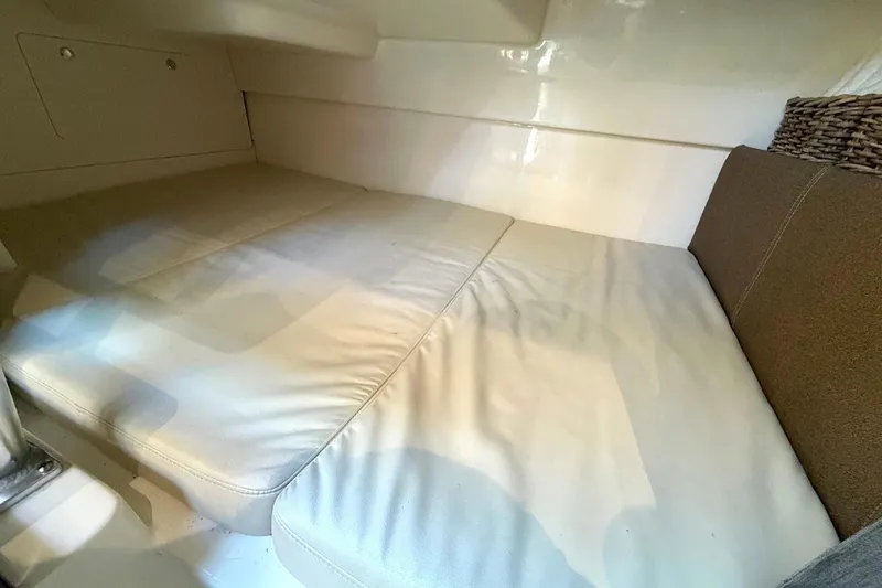 Slide: The Image of 2025 Boston Whaler 285 Conquest cabin interior with cushioned seating and storage. - 50