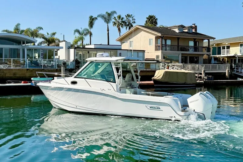 Slide: The Image of 2025 Boston Whaler 285 Conquest boat cruising in a scenic waterfront setting. - 6