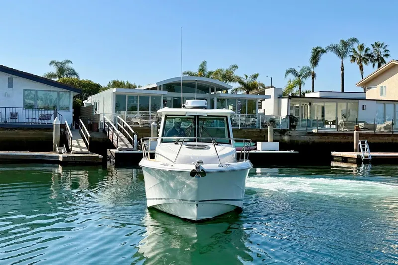 Slide: The Image of 2025 Boston Whaler 285 Conquest boat docked near modern waterfront homes. - 9