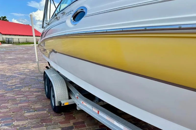 Slide: The Image of 2004 Sea Ray 270 Sundeck boat on trailer, yellow and white exterior, parked on brick pavement. - 11