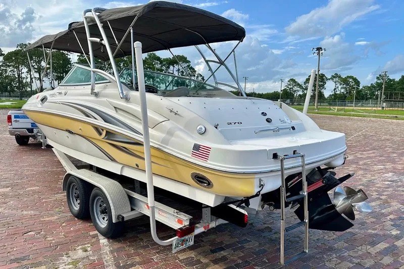 Slide: The Image of 2004 Sea Ray 270 Sundeck boat on trailer, parked outdoors, with blue sky background. - 4