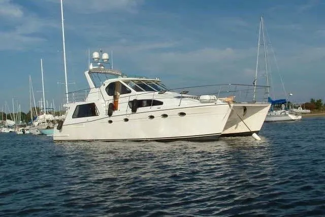Slide: The Image of 2002 Wright Catamaran C50 Pilot House Power Catamaran on calm water, clear sky background. - 0