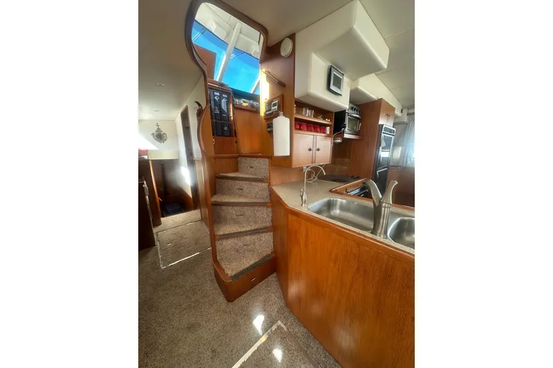 Slide: The Image of Interior of 2002 Wright Catamaran C50, featuring kitchen and stairs with wooden cabinetry. - 24