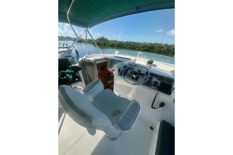 Slide: The Image of 2002 Wright Catamaran C50 Pilot House Power Catamaran helm with green canopy, docked by water. - 28