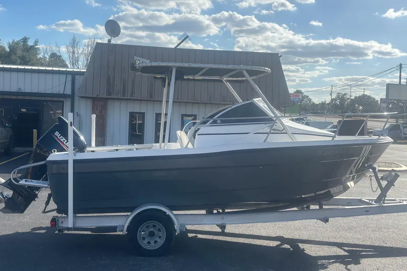 Slide: The Image of 1998 Bayliner Trophy Walkaround boat on trailer, parked outside a building under a cloudy sky. - 6