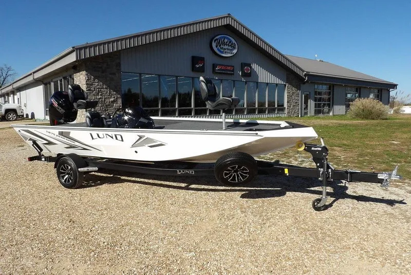 Slide: The Image of 2026 Lund 1875 Renegade boat on trailer outside marine center, sunny day. - 3