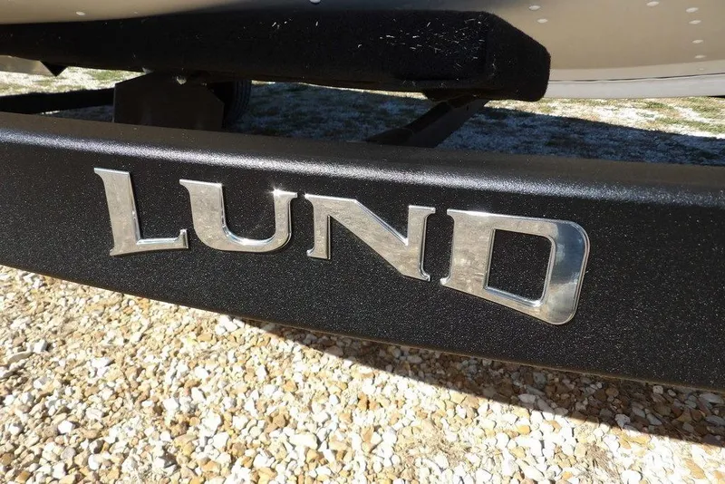 Slide: The Image of 2026 Lund 1875 Renegade boat trailer with metallic logo on gravel surface. - 37