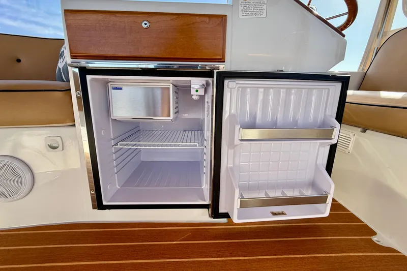 Slide: The Image of Open mini fridge on 2022 Duffy Suncruiser 22 boat, featuring wooden accents and seating. - 10