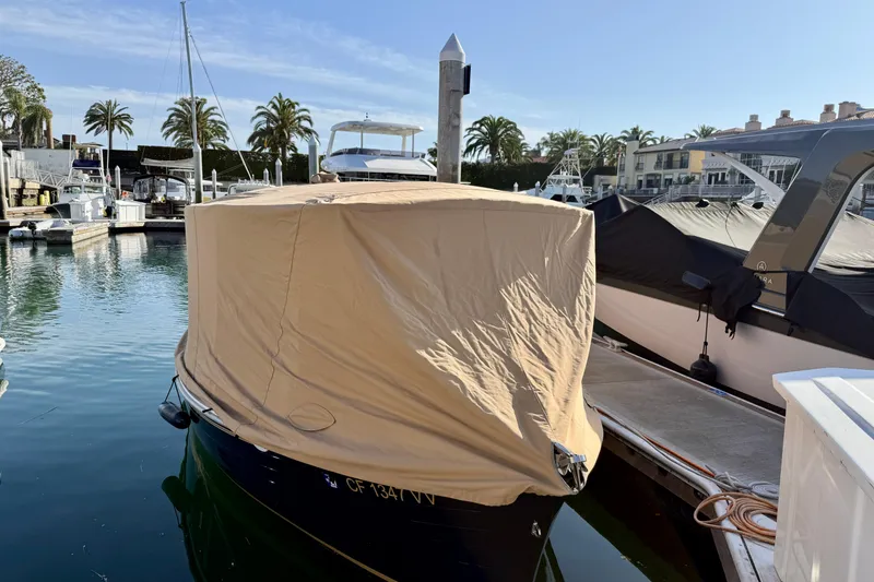 Slide: The Image of 2022 Duffy Suncruiser 22 boat covered at marina, surrounded by palm trees and yachts. - 24