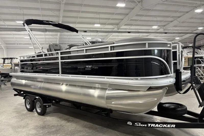 The Image of 2026 Sun Tracker SportFish 22 DLX pontoon boat on trailer in showroom. - 0
