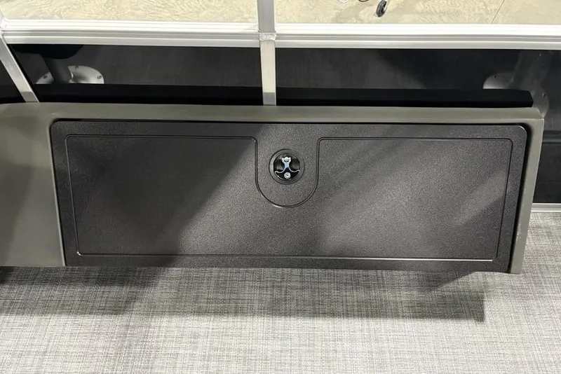Slide: The Image of 2026 Sun Tracker SportFish 22 DLX storage compartment with secure latch on a textured surface. - 28