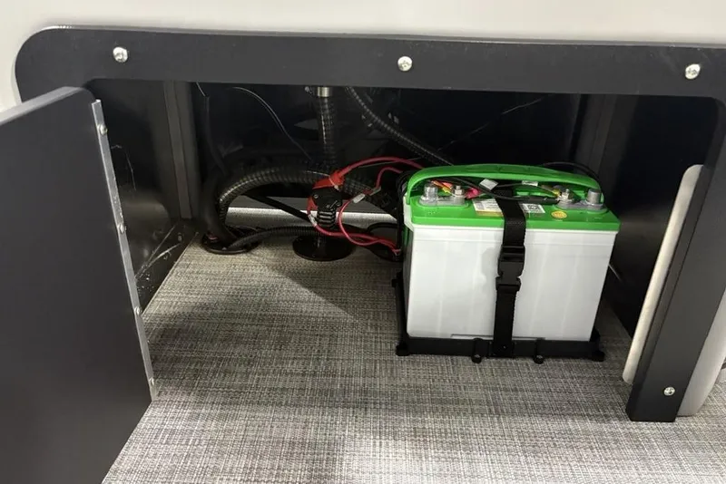 Slide: The Image of Battery compartment of 2026 Sun Tracker SportFish 22 DLX boat, featuring secured battery. - 31