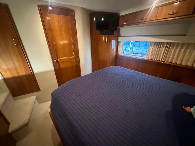 Slide: The Image of Luxurious 2004 Carver 396 Motor Yacht bedroom with nautical-themed bedding and elegant wood finishes. - 20