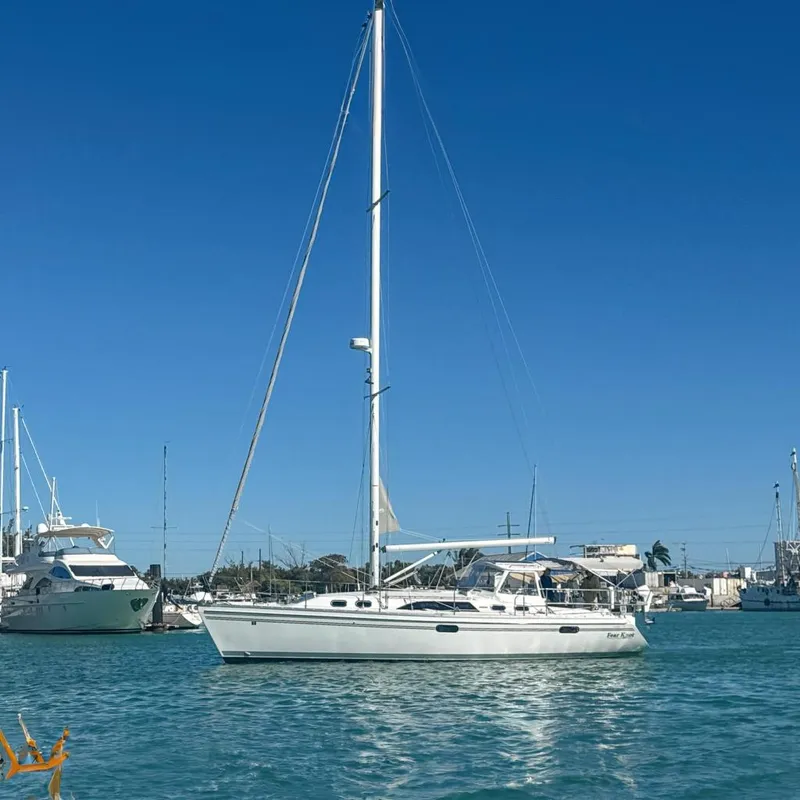 The Image of 2022 Catalina 385 sailboat docked in a marina with palm trees and clear blue sky. - 0