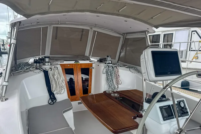 Slide: The Image of 2022 Catalina 385 yacht cockpit with navigation equipment, seating, and wooden table. - 19