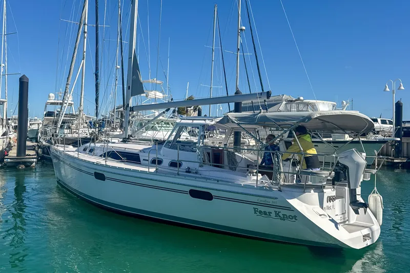 Slide: The Image of 2022 Catalina 385 sailboat in marina, two people onboard, surrounded by other boats. - 8