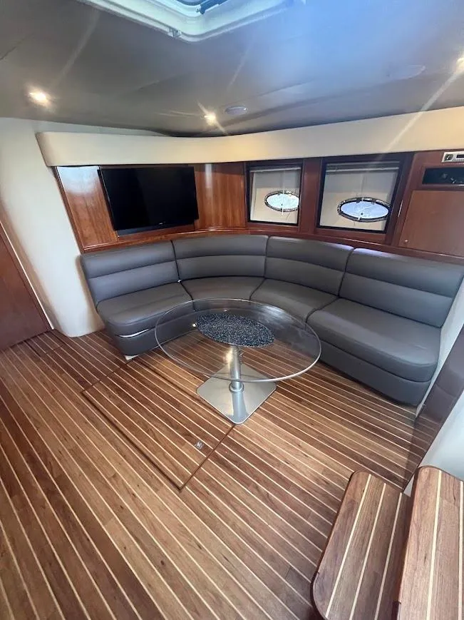 Slide: The Image of 2000 Carver 440 Hardtop Express interior with curved seating, wood flooring, and a glass table. - 14