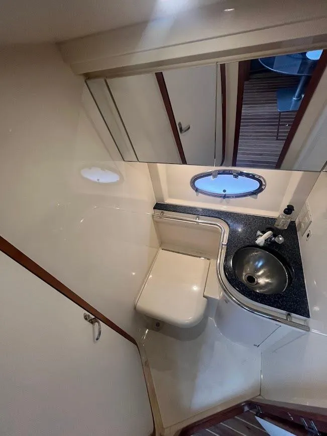 Slide: The Image of 2000 Carver 440 Hardtop Express yacht bathroom with sink, mirror, and porthole window. - 25