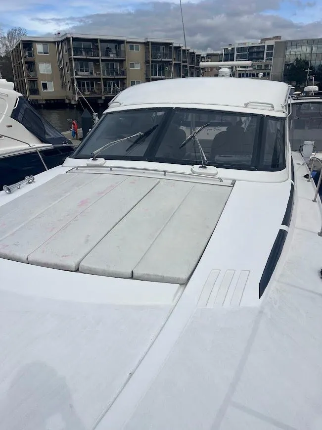 Slide: The Image of 2000 Carver 440 Hardtop Express yacht docked near modern buildings. - 28