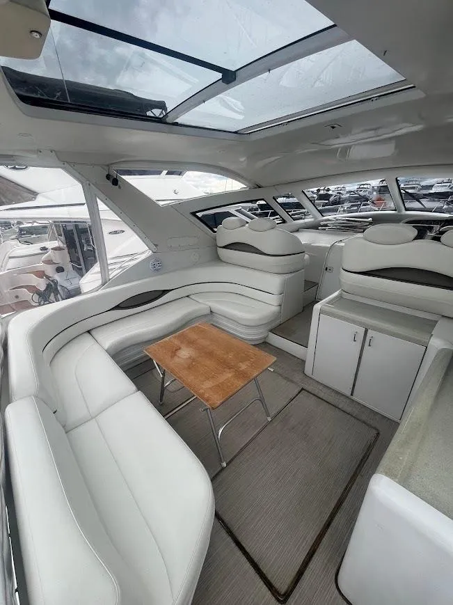 Slide: The Image of Interior of 2000 Carver 440 Hardtop Express yacht with white seating and wooden table. - 7