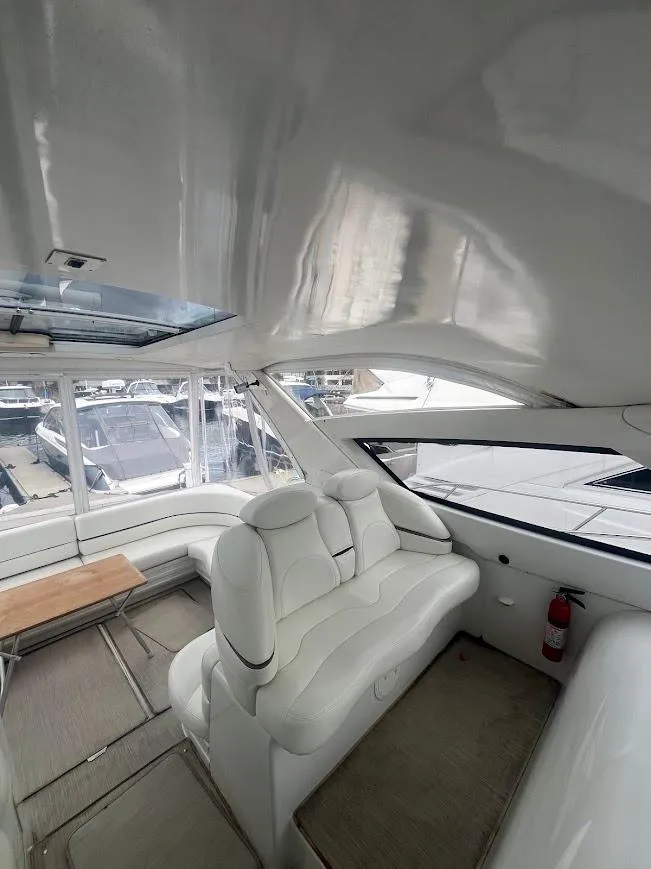 Slide: The Image of Interior of 2000 Carver 440 Hardtop Express yacht with white seating and panoramic windows. - 9