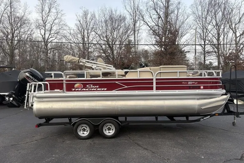 The Image of 2019 Sun Tracker Fishin' Barge 20 DLX pontoon boat on trailer, parked outdoors. - 0
