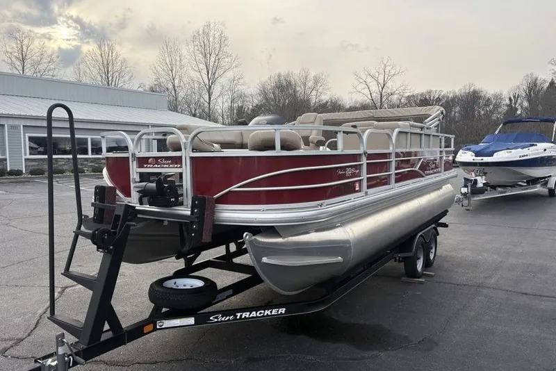 Slide: The Image of 2019 Sun Tracker Fishin' Barge 20 DLX pontoon boat on trailer in parking lot. - 2