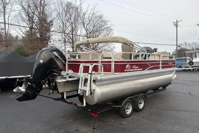 Slide: The Image of 2019 Sun Tracker Fishin' Barge 20 DLX pontoon boat on trailer, featuring Mercury outboard motor. - 6