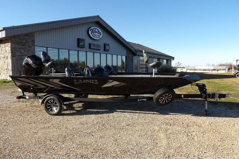 Slide: The Image of 2026 Lund 1975 Renegade boat on trailer outside marine center. - 2