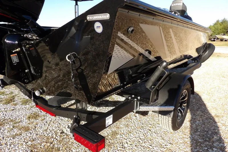 Slide: The Image of 2026 Lund 1975 Renegade boat on trailer, shiny black finish, parked on gravel. - 42