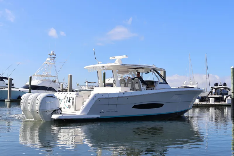 Slide: The Image of 2022 Regal 38 SAV boat docked in marina, featuring triple Yamaha engines. - 14