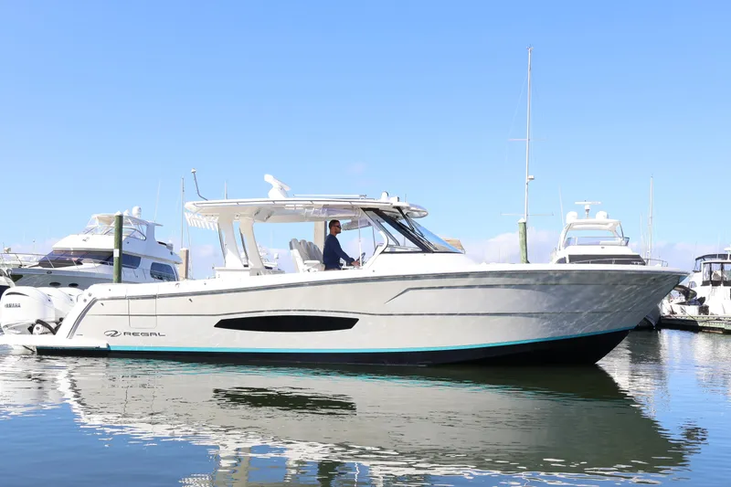 Slide: The Image of 2022 Regal 38 SAV boat docked in marina, clear sky, calm water. - 4